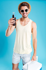 Fototapeta na wymiar Smiling young man holding cooling bag and bottle of soda