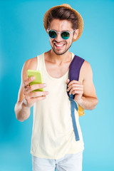 Cheerful young man with backpack using mobile phone