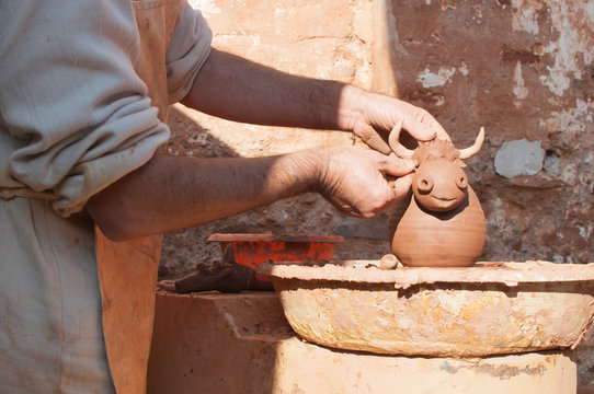 Potter working the clay making a torus-shaped piggy bank