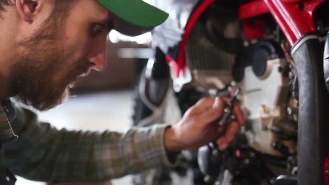 male sportsman repairing his enduro motorcycle