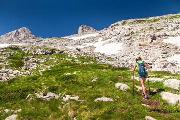 Naklejka premium woman trekking among rocky mountains on summer grass