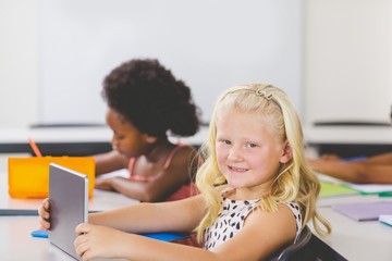 Fototapeta na wymiar Schoolgirl using digital tablet in classroom