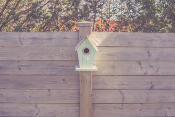 Cute birdhouse on a wooden fence