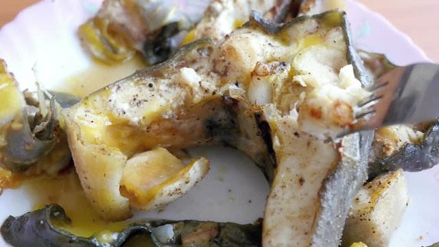 4k of Tasty fried fish steaks in a plate. check the readiness of the fish, picking fork
