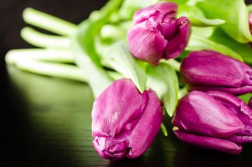 Obraz premium Bunch of purple tulips on dark wooden background