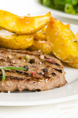 Beef burger patty with the roasted potato, side salad and spices on wh