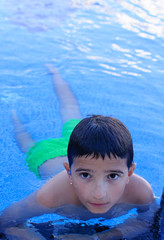 boy swimming in the pool and looking at camera