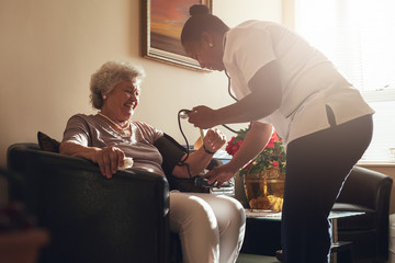 Nurse measuring blood pressure of senior patient in retirement h