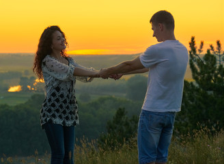 romantic couple holding hands at sunset on outdoor, beautiful landscape and bright yellow sky, love tenderness concept, young adult people