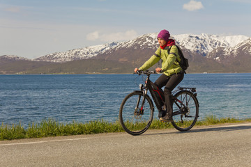 junge Frau (Mädchen) fährt Fahrrad (E-Bike) auf Straße vor Bergen young woman (girl) riding a bicycle (e-bike) on road in front of mountains 