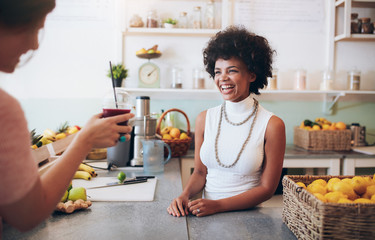 Smiling young woman talking to a customer in juice bar