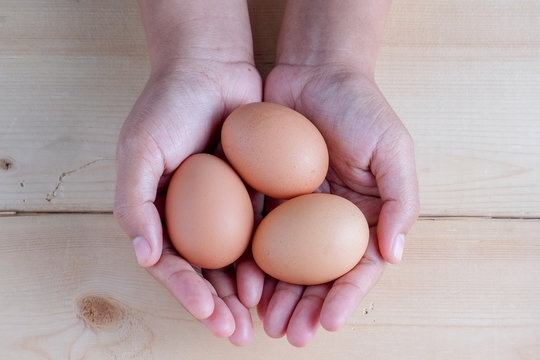hand holding egg on wooden background