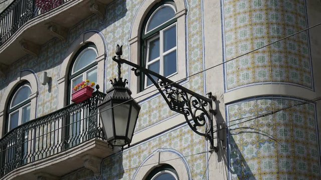A dolly shot of a typical Portuguese facade with traditional tiles and a street lamp, in Portugal.