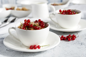 Two white cups with red currant. Light blue background. 