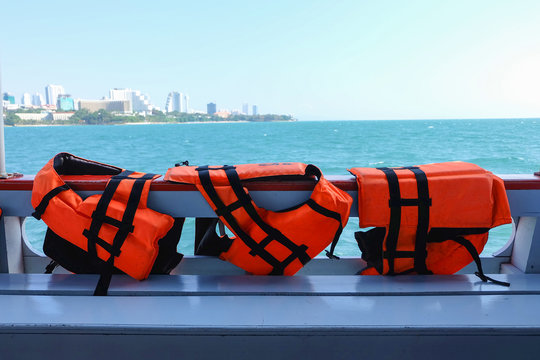 Safety life vests in orange hanging on ferry boat sailing in sea  