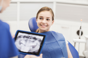 dentist with x-ray on tablet pc and girl patient