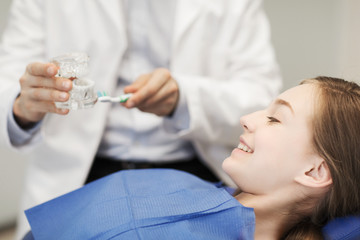 Obraz na płótnie Canvas happy dentist showing jaw layout to patient girl