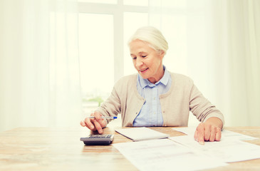 senior woman with papers and calculator at home