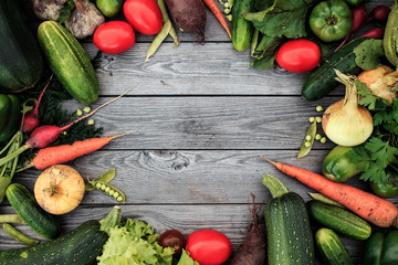 Young spring vegetables on wooden chalkboard from above. Carrots, tomatoes, zucchini, leek, radish, parsley - fresh harvest from the garden. Top view point