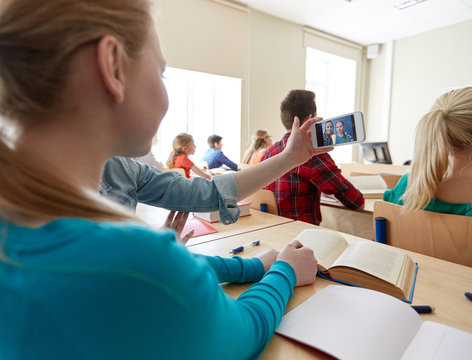 student girls taking smartphone selfie at school