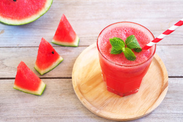 Close up of a glass of watermelon juice with mints  on a wooden background. 