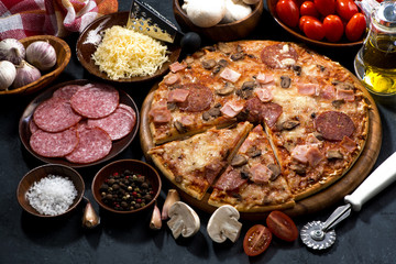 pizza with salami and ingredients on a dark background,top view