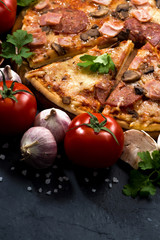 pizza with sausage and cheese and ingredients on dark background