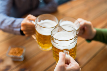 close up of hands with beer mugs at bar or pub