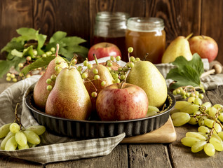 Plate with pears and apples on wooden background. Glass jar of honey. Thanksgiving dinner.