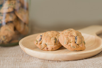 Oat cookies with pumpkin seeds and raisin on a wooden plate.