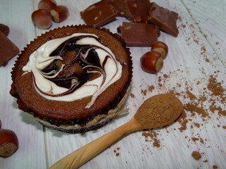 шоколадное пирожное с фундуком и кремом  лежит на светлых деревянных досках   