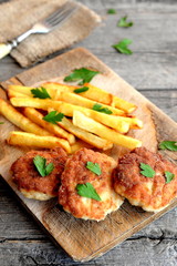 Fried patties cooked with Turkey mince. Fried potatoes. Turkey meat patties served with potatoes and garnished with parsley on a wooden board. Rustic stile. Closeup