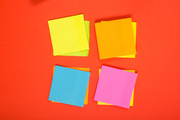 Office table desk with set of colorful supplies, white blank note pad, cup, pen, pc, crumpled paper, flower on red background. Top view and copy space for text