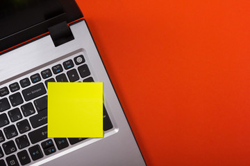 Office table desk with set of colorful supplies, laptop and reminder sticky note on red background. Top view. Copy space for text
