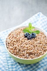 Buckwheat porridge in a bowl with mint leaves and blueberries.