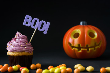 Halloween cupcake and pumpkin on black background
