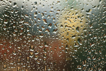 Rain drops on window with house and church in background