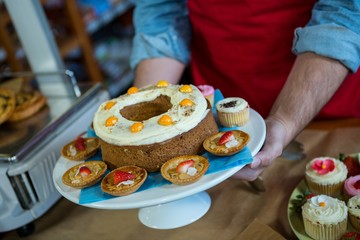 Mid section of staff holding a tray of desserts
