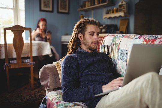 Hipster man using laptop while woman sitting at home