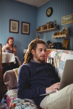 Man using laptop while sitting on sofa at home