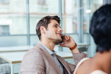 Happy man talking on cell phone in office