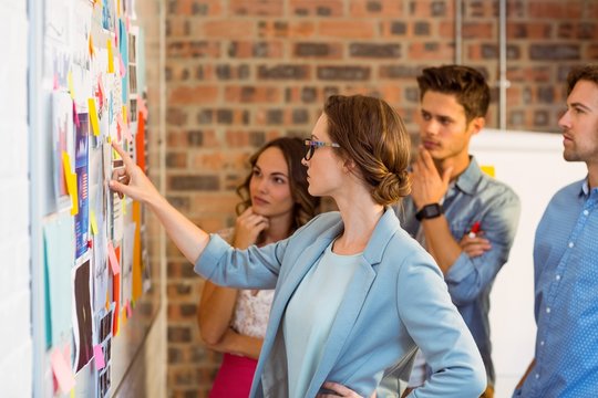 Business Executives Looking At Sticky Notes On Whiteboard