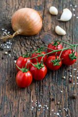 Rispentomaten Knoblauch Zwiebel auf Holzbrett