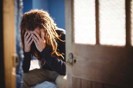 Sad hipster man sitting on bed