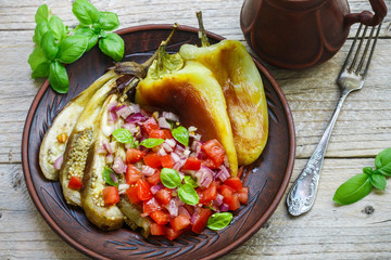 Baked vegetables. Bell peppers and eggplant cooked on the fire. Served with a salad of tomatoes, red onion and Basil. Rustic style
