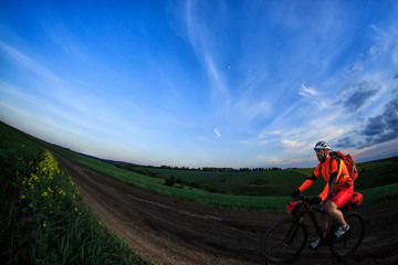 Obraz premium Mountain bikeer rides on the trail against beautiful sunset
