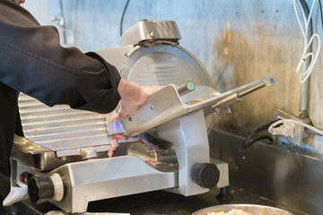 Chef operating meat slicer machine
