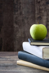 School supplies and green apple on rustic wooden background

