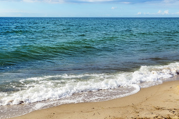blue sea with horizon and foam waves on the sand beach,  background with copy space