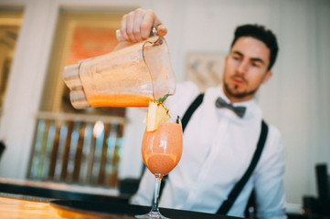 Barman preparing a pineapple and strawberry cocktail